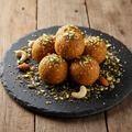 Protein Laddoos - golden laddoos garnished with crushed nuts and seeds on a dark slate plate